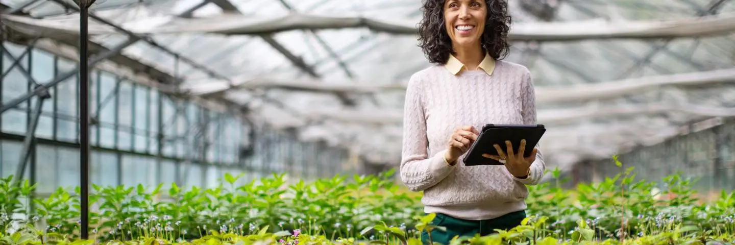 A woman standing in a greenhouse checking on plant growth