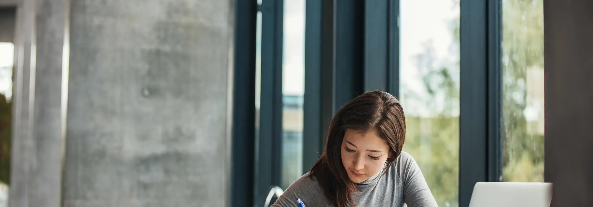 Woman writing at desk beside window