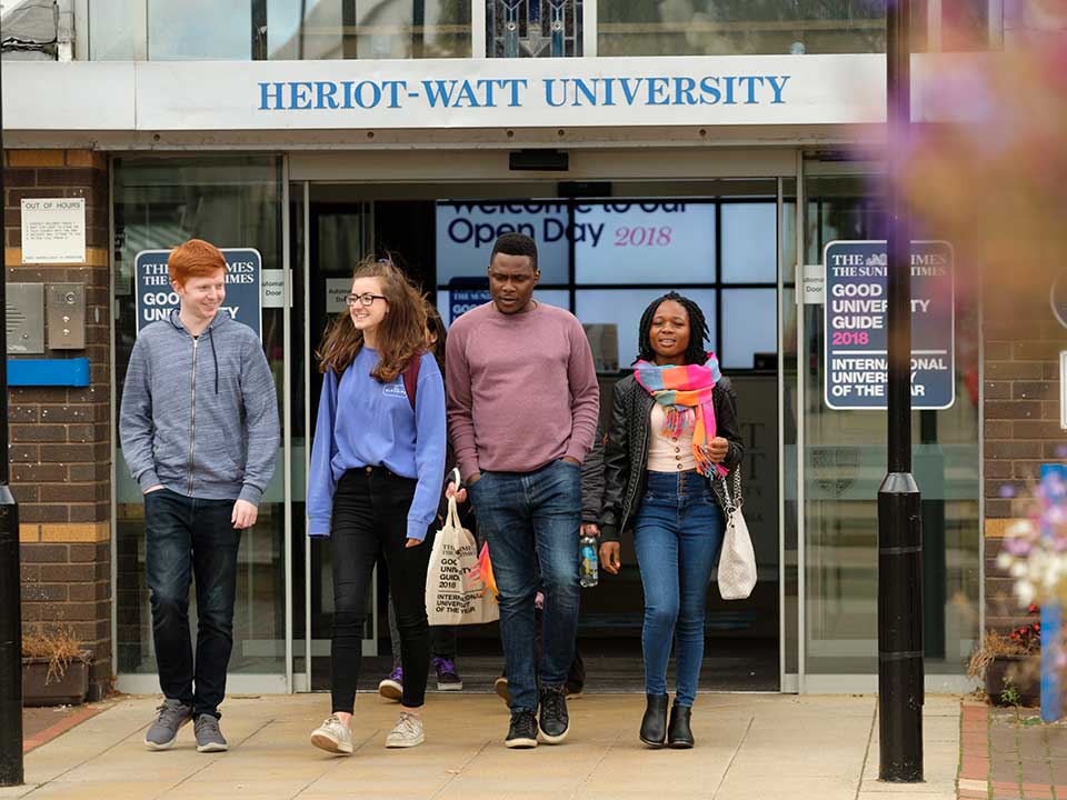  Four students walking outside reception on Heriot-Watt Edinburgh campus