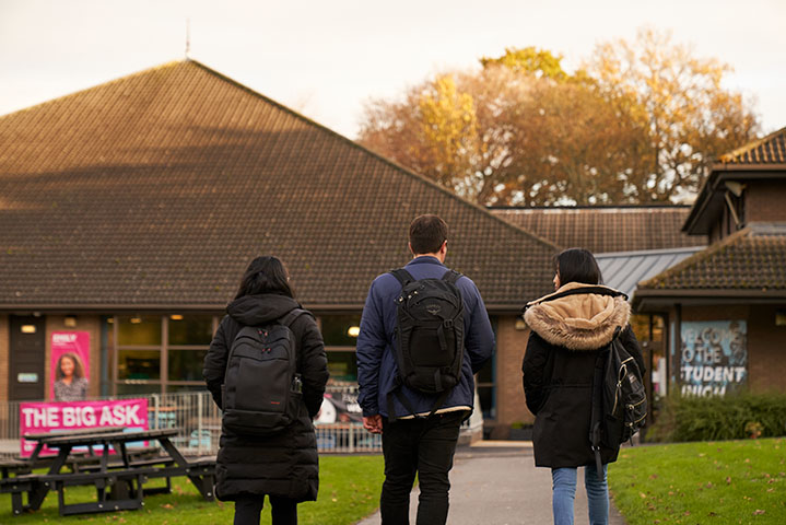 Three students on the Heriot-Watt Edinburgh campus walking and talking