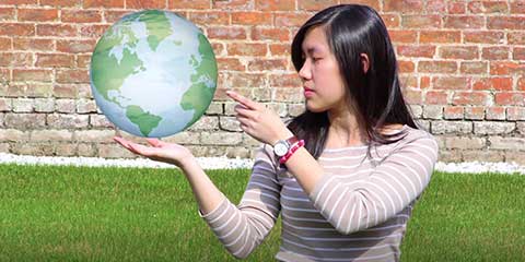 Person holding globe in front of a brick wall