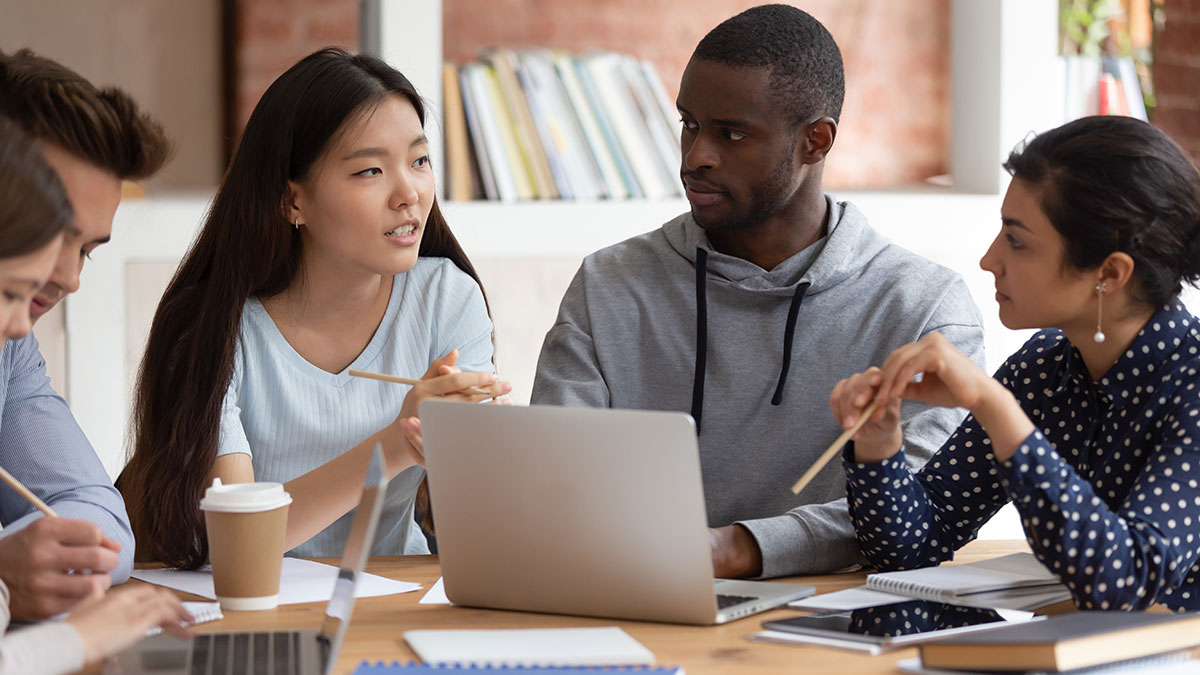 A diverse group have a discussion around a desk