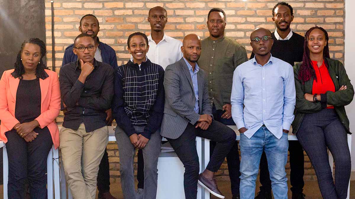 Ten Rwandan MSc Renewable Energy students stand behind or perch upon a bank of tables.