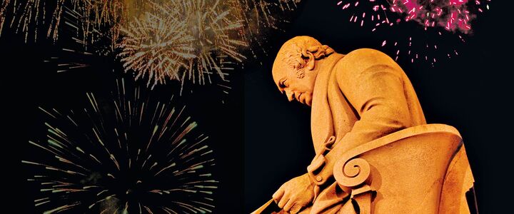 The James Watt statue at the Edinburgh Campus lit up by fireworks exploding overhead