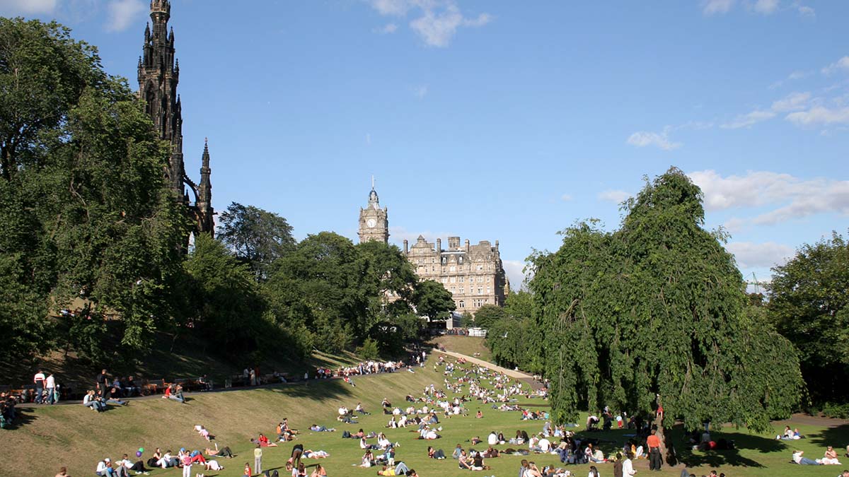 People sitting on the grass in Princes Street Gardens on a sunny day