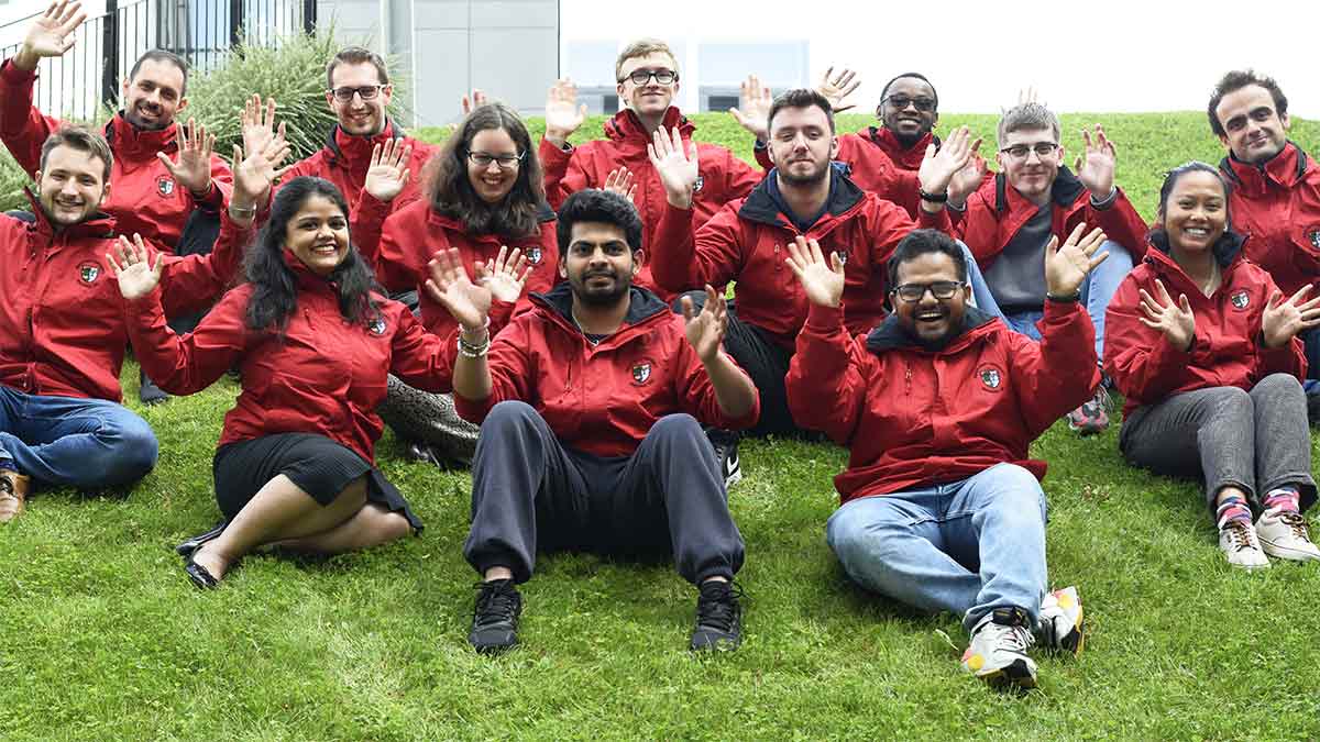 Residence life 2021-2022 team sitting on a hill wearing matching red team jackets