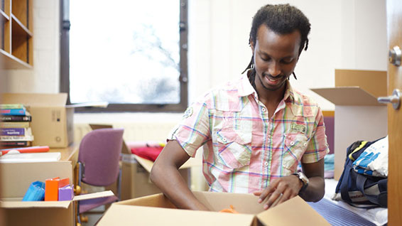 Student unpacking boxes in room