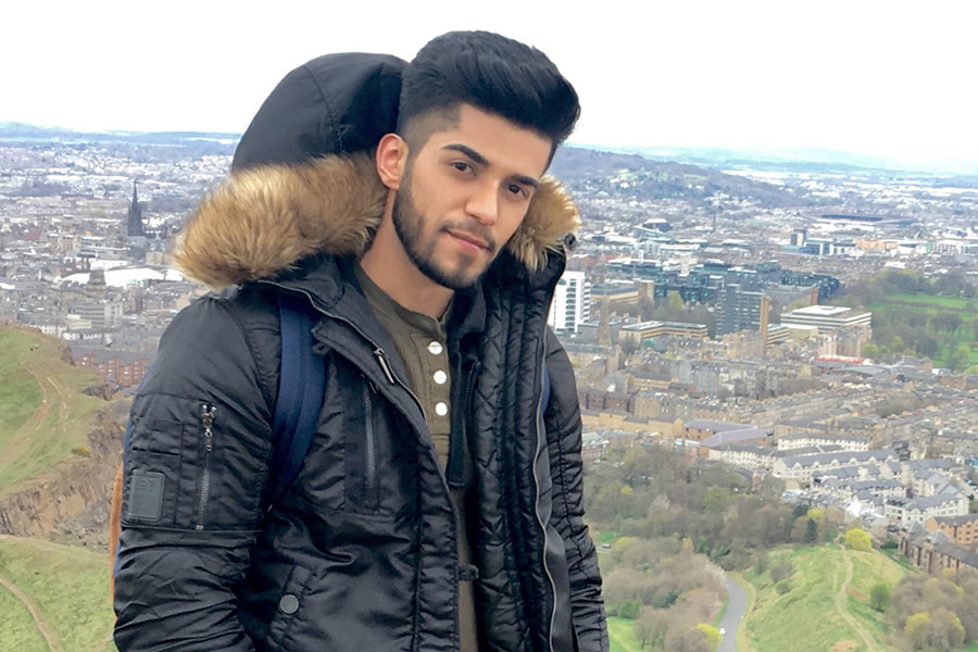 Vishant Kalwani, Go Global student studying abroad in Edinburgh, stands on Arthurs Seat overlooking Edinburgh City