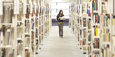 Student walking between shelves of books