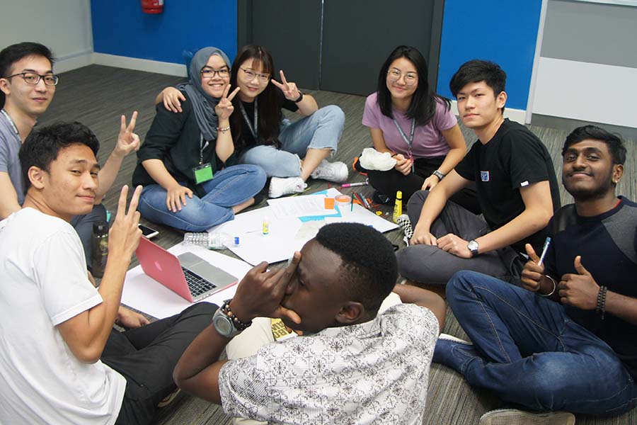 Group of students seated on the carpet collaborate in a workshop activity