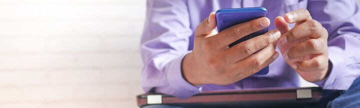 Man in purple shirt and blue jeans using his smart phone