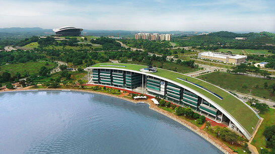 Aerial view of the Malaysia Campus building with grassed roof visible and lake in the foreground