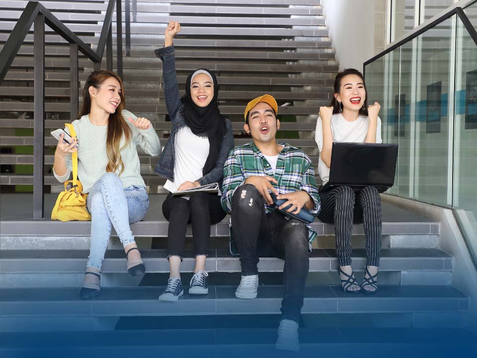 A group of students sat on some stairs smiling and laughing