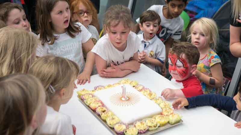 Children blowing out 1st birthday cake