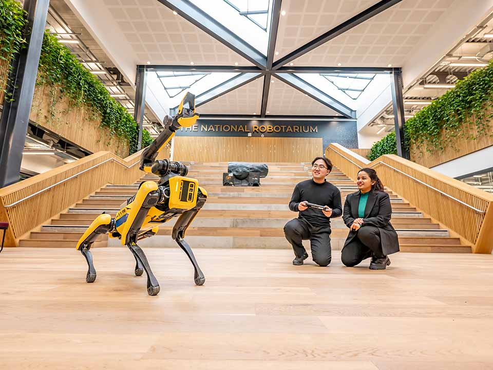 Two students operate a robot dog using a handheld controller