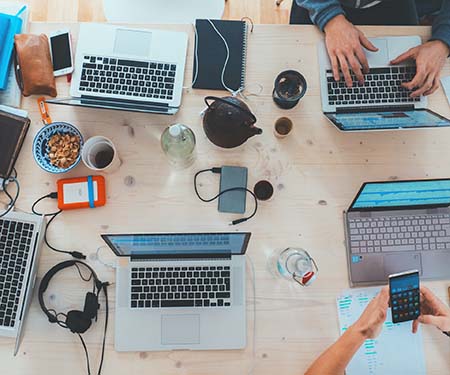 Group of people using laptops around a rectangular table