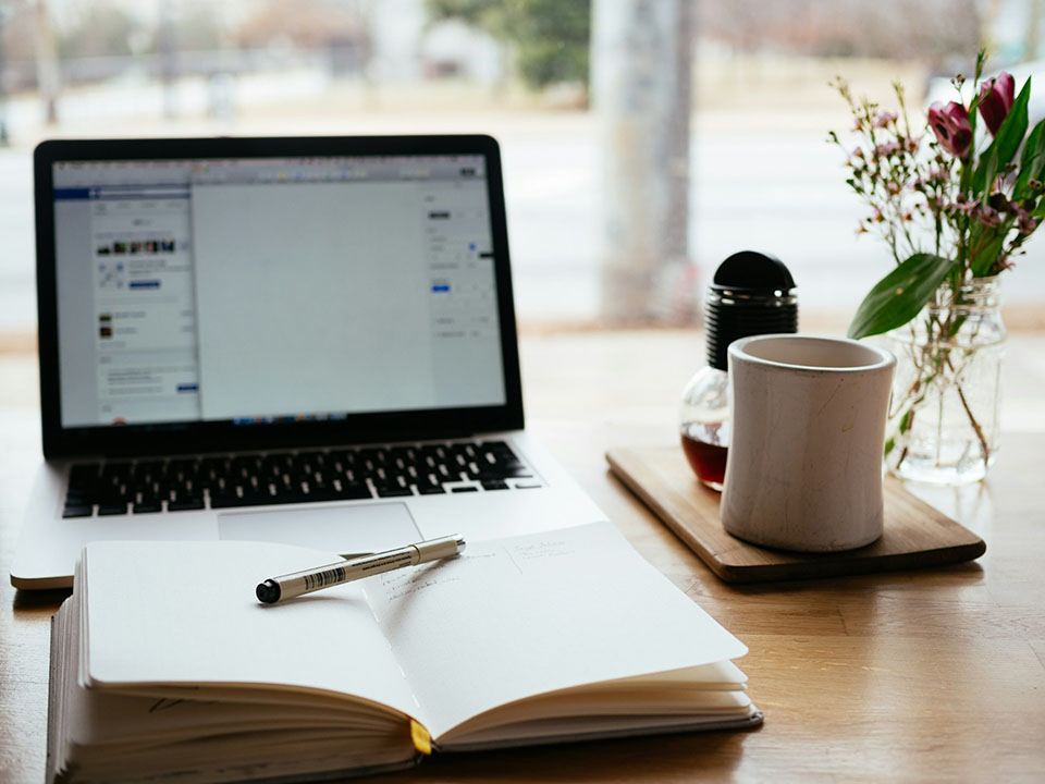 Notebook and pen placed in front of a laptop ready for note taking