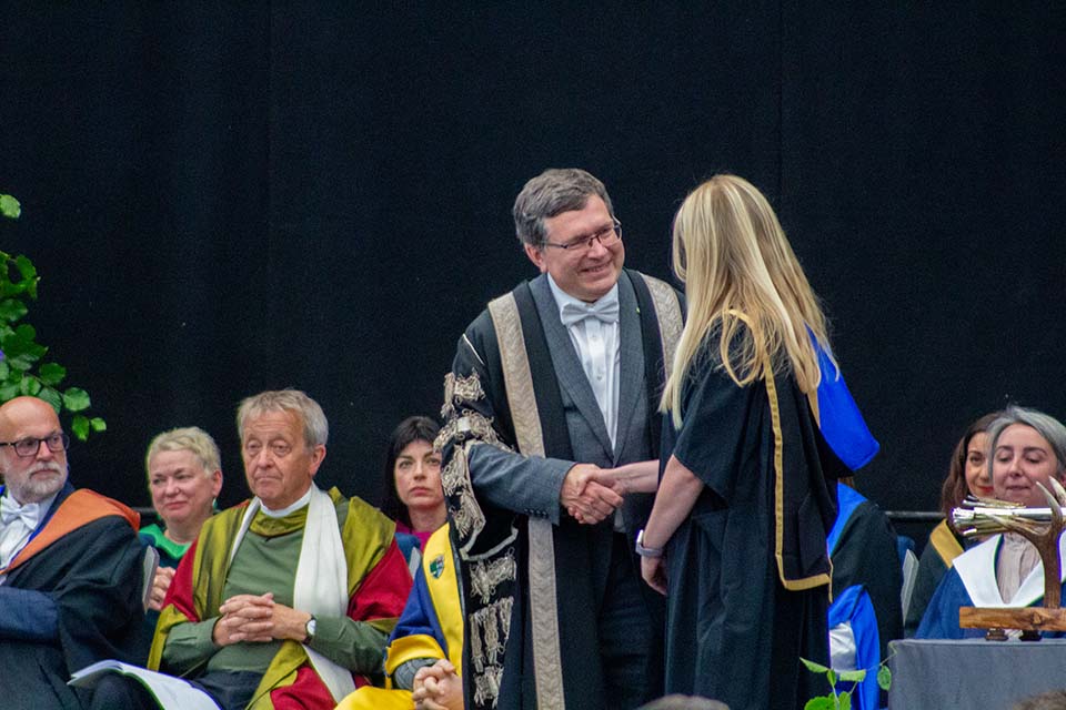 A student on stage at graduation shaking the chancellors hand