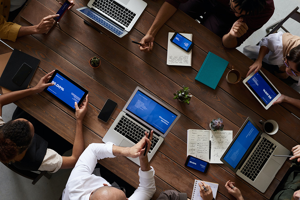 People with laptops gathered round a table working on a project