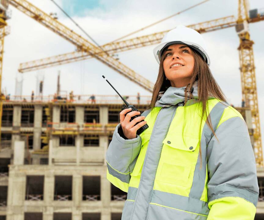 female engineer in high visibility jacket talking into walkie talkie on construction site