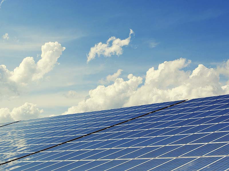 Solar panels against a blue sky with clouds