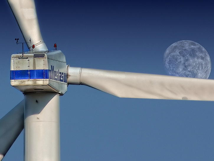 Rear view of a wind tubine with the moon in the distance