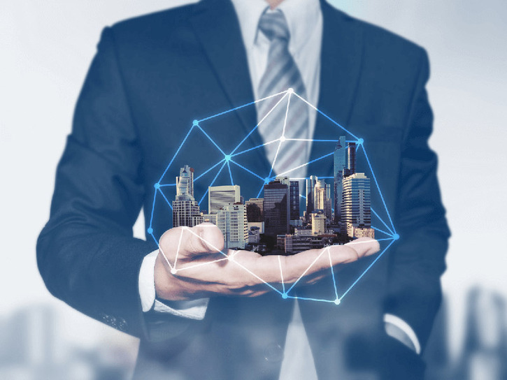 person wearing suit, holding city in their hand