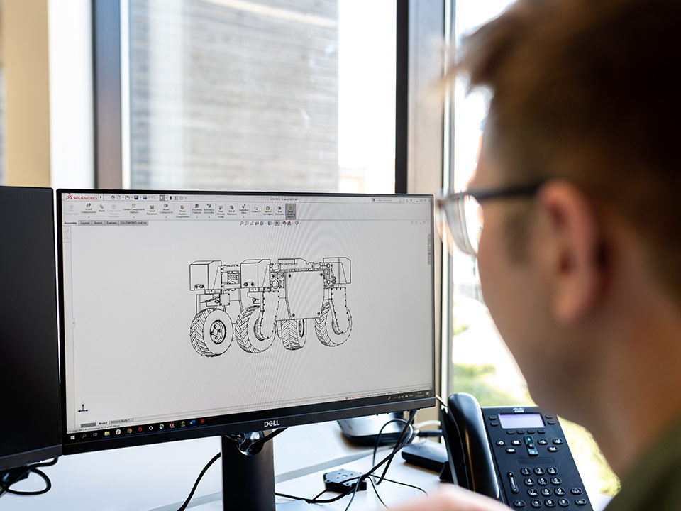 a man creating a technical drawing of a robot on a computer