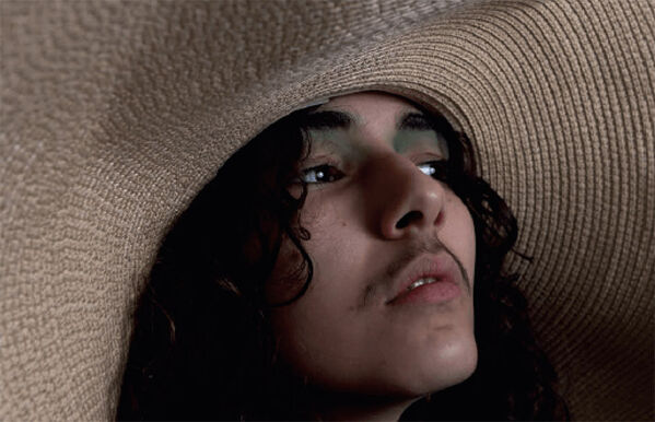 close up of person wearing green eyeshadow and a large straw hat