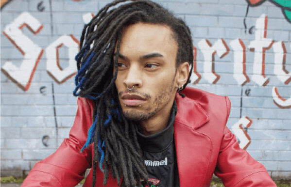 headshot of perosn with dreads and wearing red leather jacket whilst sat on ground