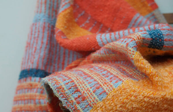 orange, yellow and blue knitted blanket draped over chair