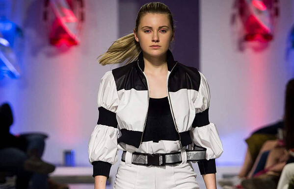 female model walking catwalk, wearing a black and white block colour cropped jacket and white jeans