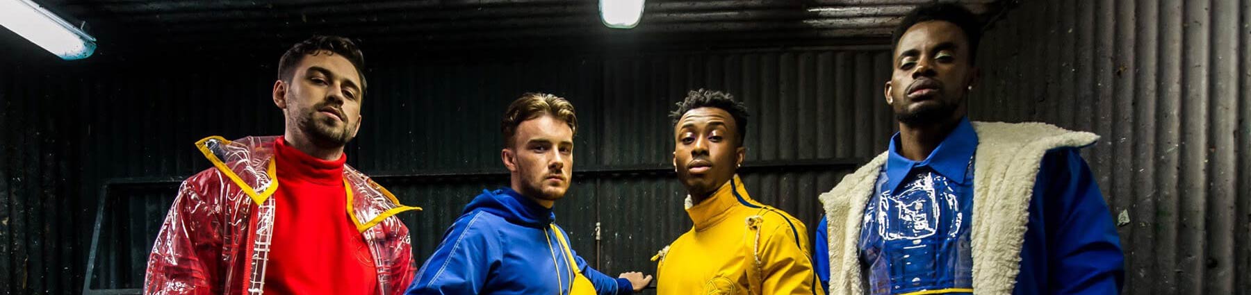 headshot of four male models in warehouse, wearing primary coloured street wear