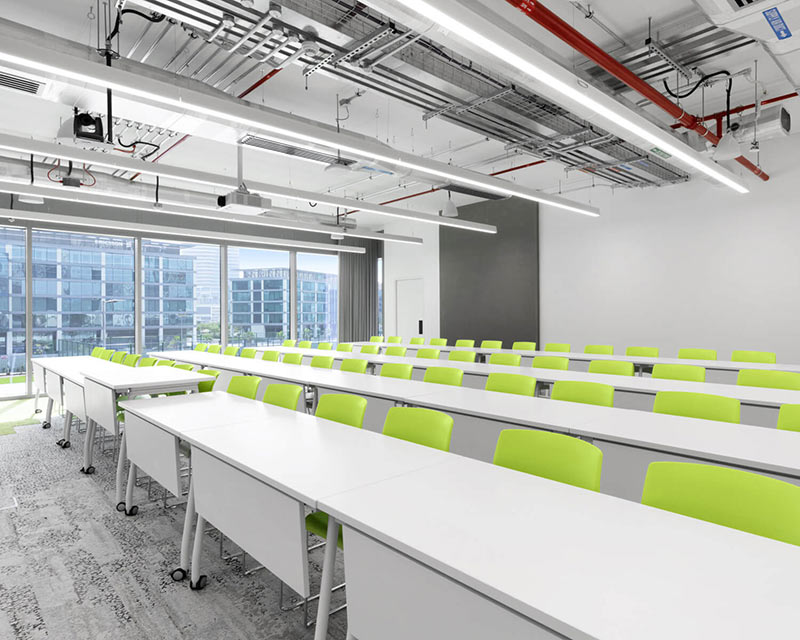 empty lecture hall with rows of white desk and lime green chairs