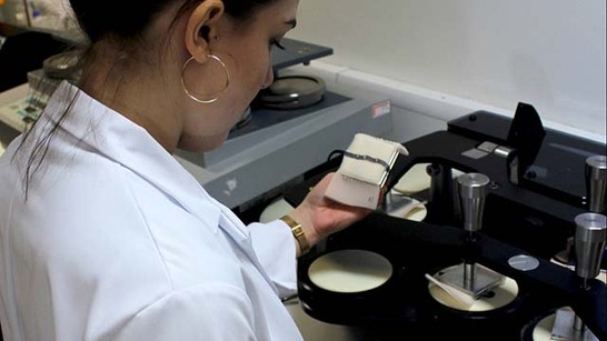 Student in white lab coat working in laboratory at School of Textiles and Design