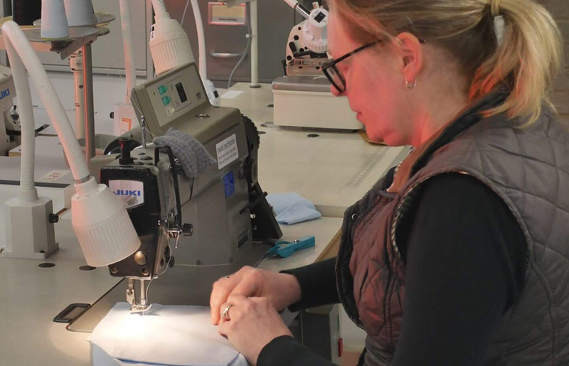 Staff member using sewing machine to make medical outfit