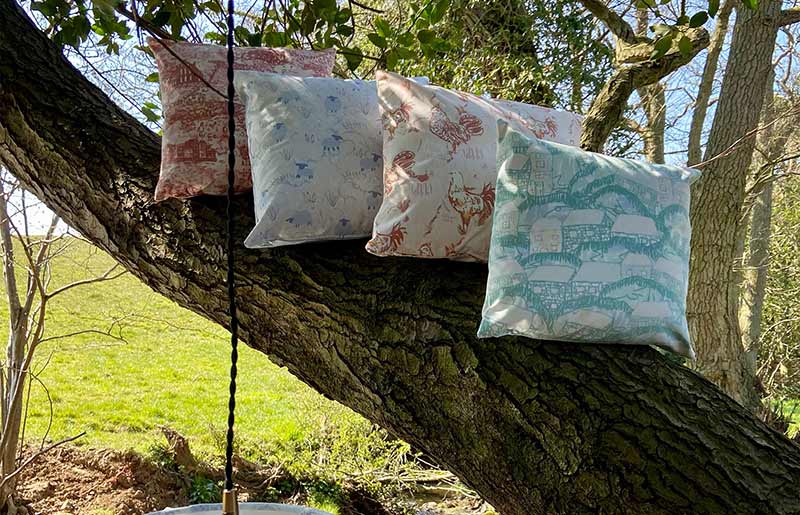 4 blue, white and pink floral print cushions in a row on a tree