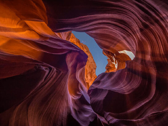 upwards shot of red canyon rocks breaking into sky in centre