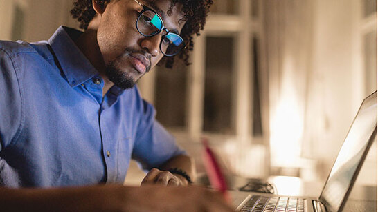 Male student working on laptop at home