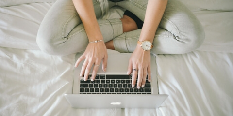 Student using laptop on bed
