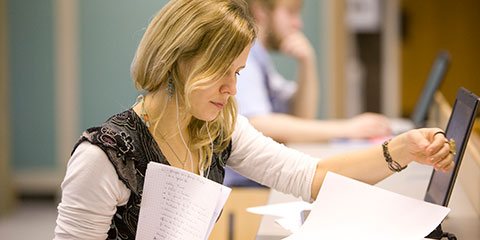 Student reading paper beside computer
